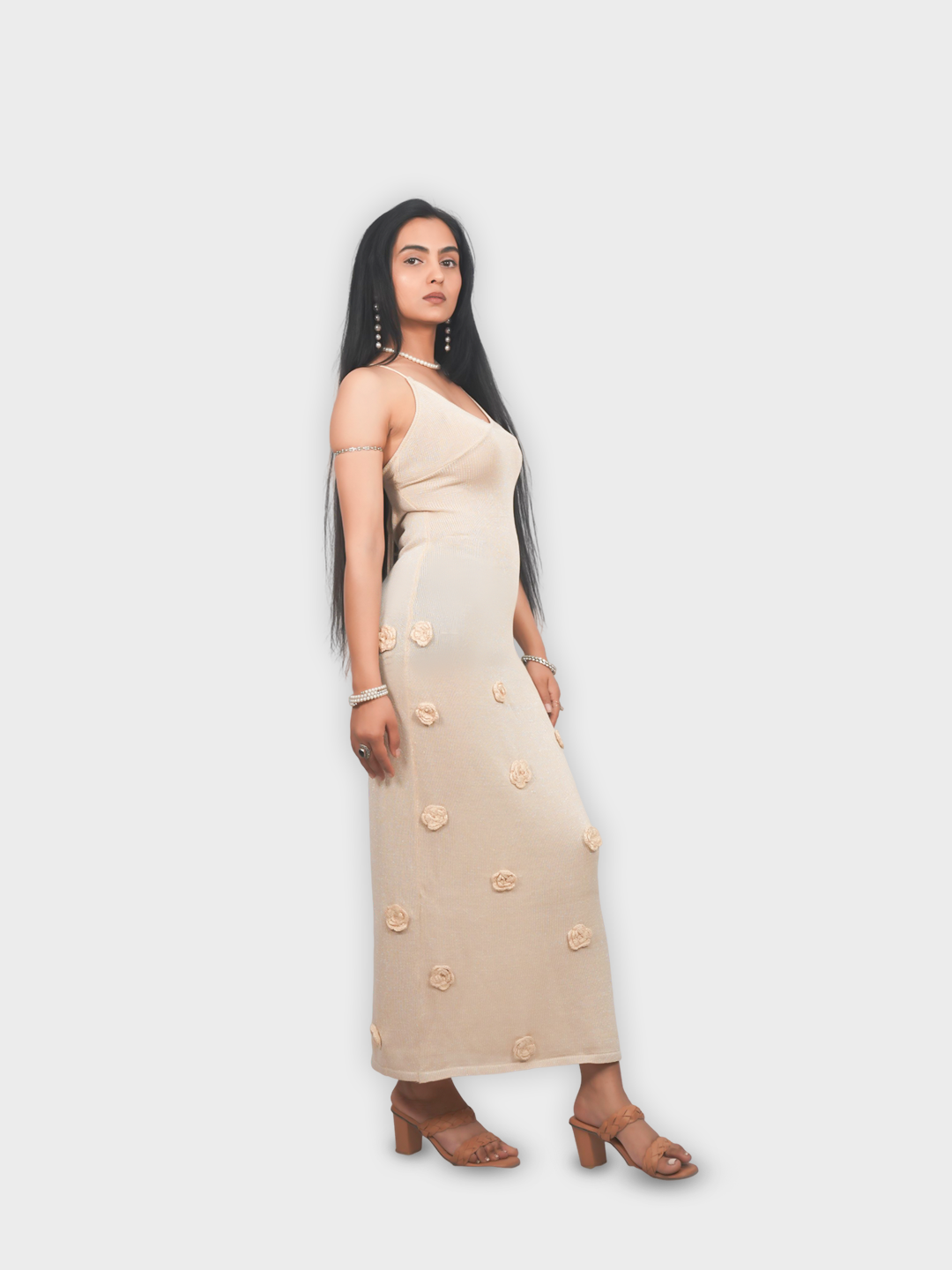 Woman wearing a beige dress with floral embellishments on a white background