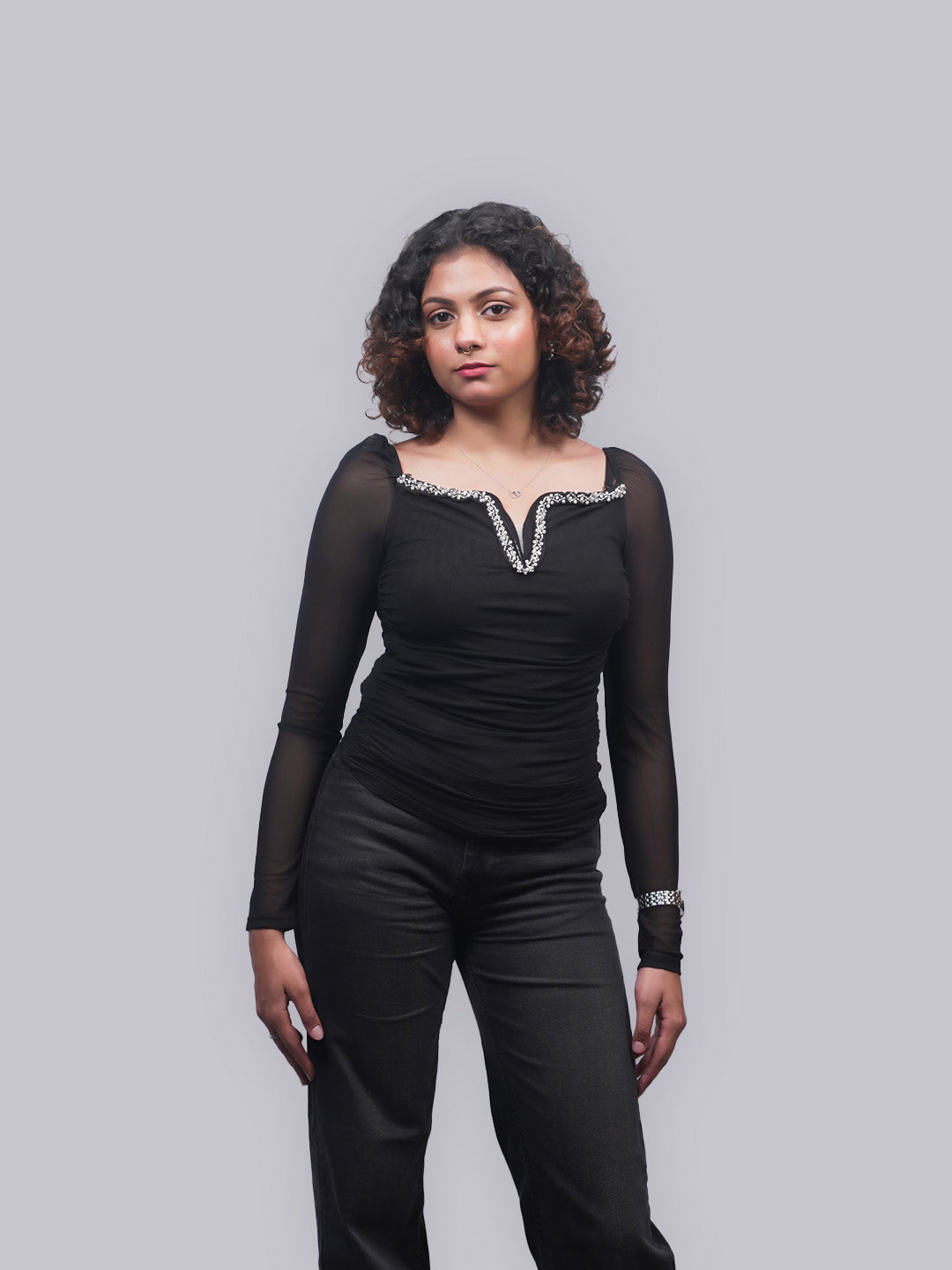 A woman modeling a black long-sleeve top with a scoop neckline trimmed.