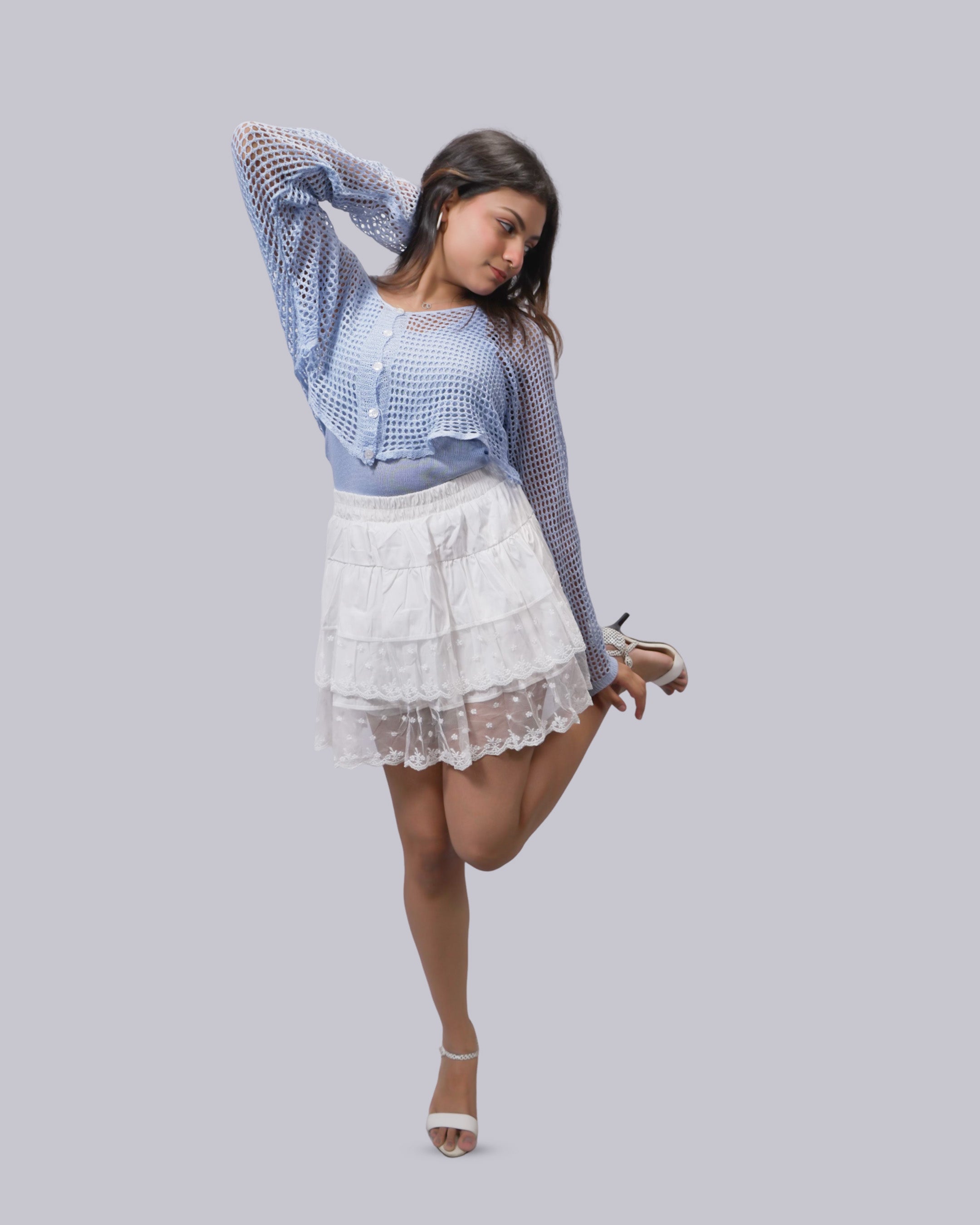 A woman modeling a light blue and white checkered crochet cardigan with long sleeves.
