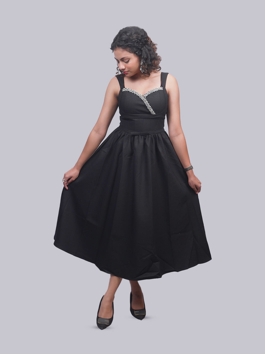 A woman modeling a sleeveless black midi dress with a structured waist and a decorative.