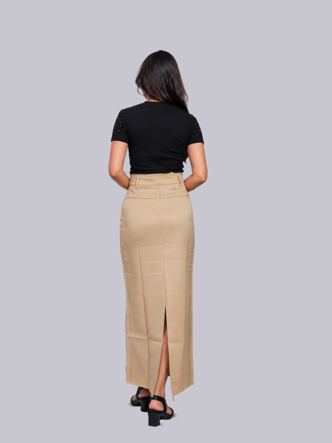 A woman shown from the back wearing a beige high-waisted midi skirt with a front slit