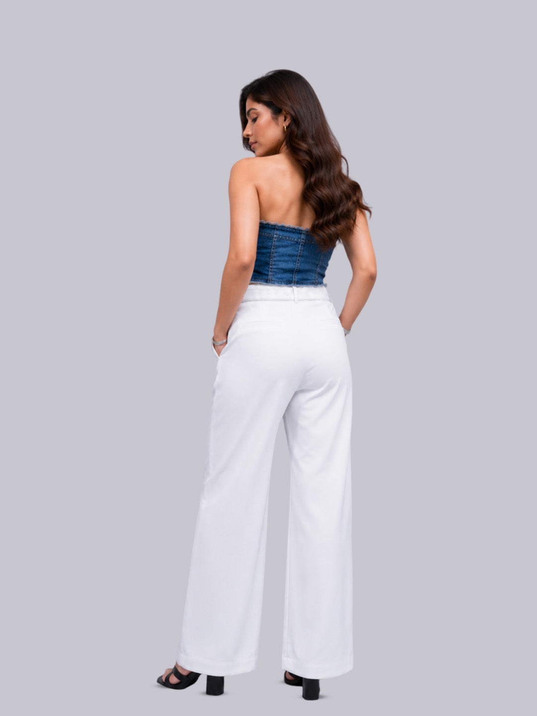 A woman shown from the back wearing white wide-leg trousers