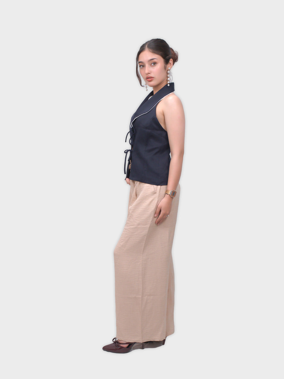 Woman wearing a navy sleeveless top and beige pants