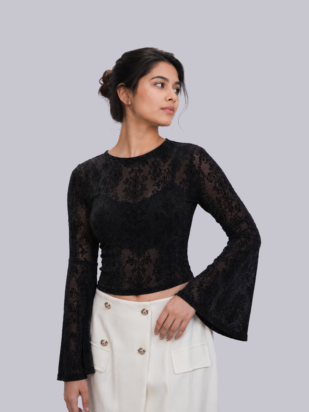 A woman modeling a black long-sleeve lace crop top with flared bell sleeves.