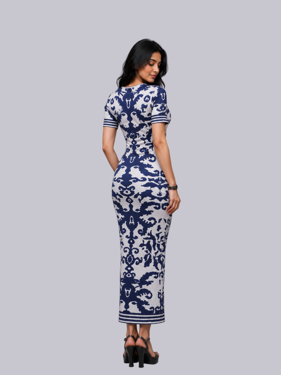 A woman modeling a fitted short-sleeve maxi dress with a navy blue and white damask pattern.