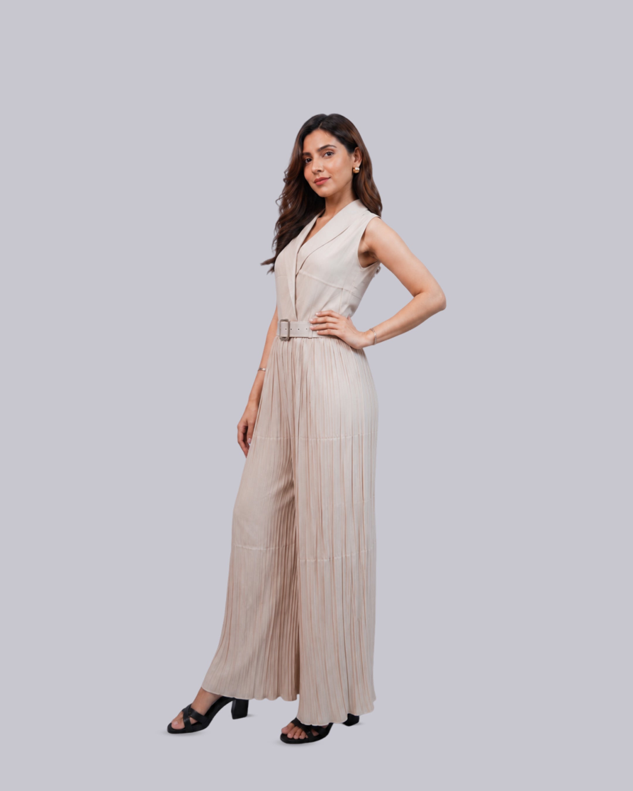 A sleeveless, light beige pleated jumpsuit with a wrap-style