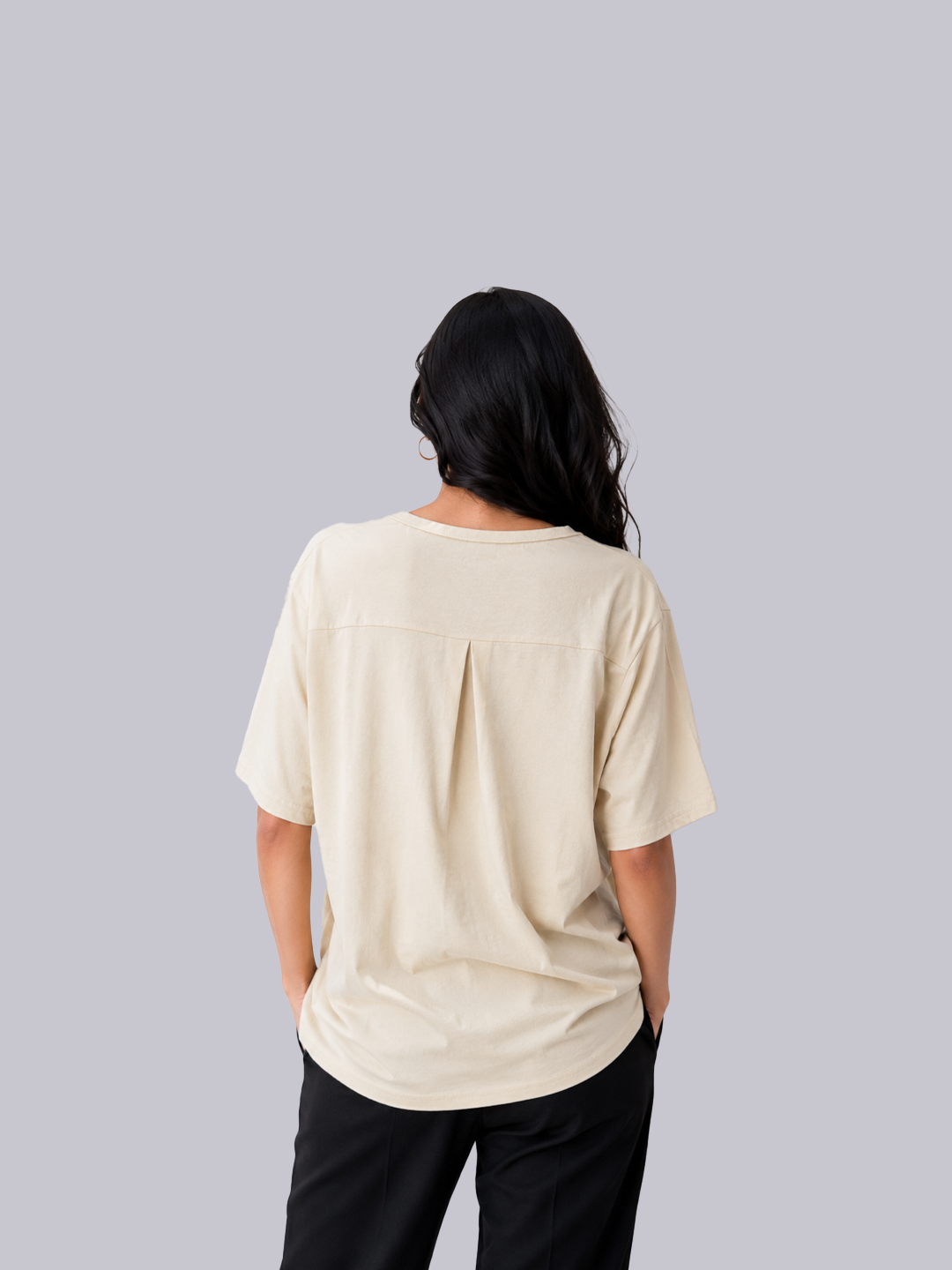 A woman viewed from behind wearing a cream-colored short-sleeve top and black pants.