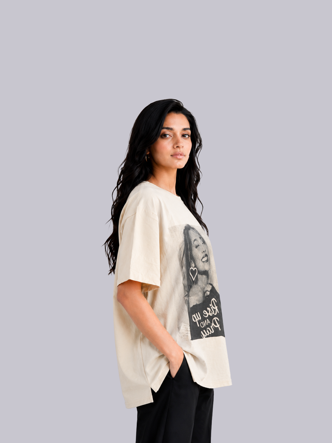 A woman modeling an oversized cream-colored t-shirt with a black and white graphic.