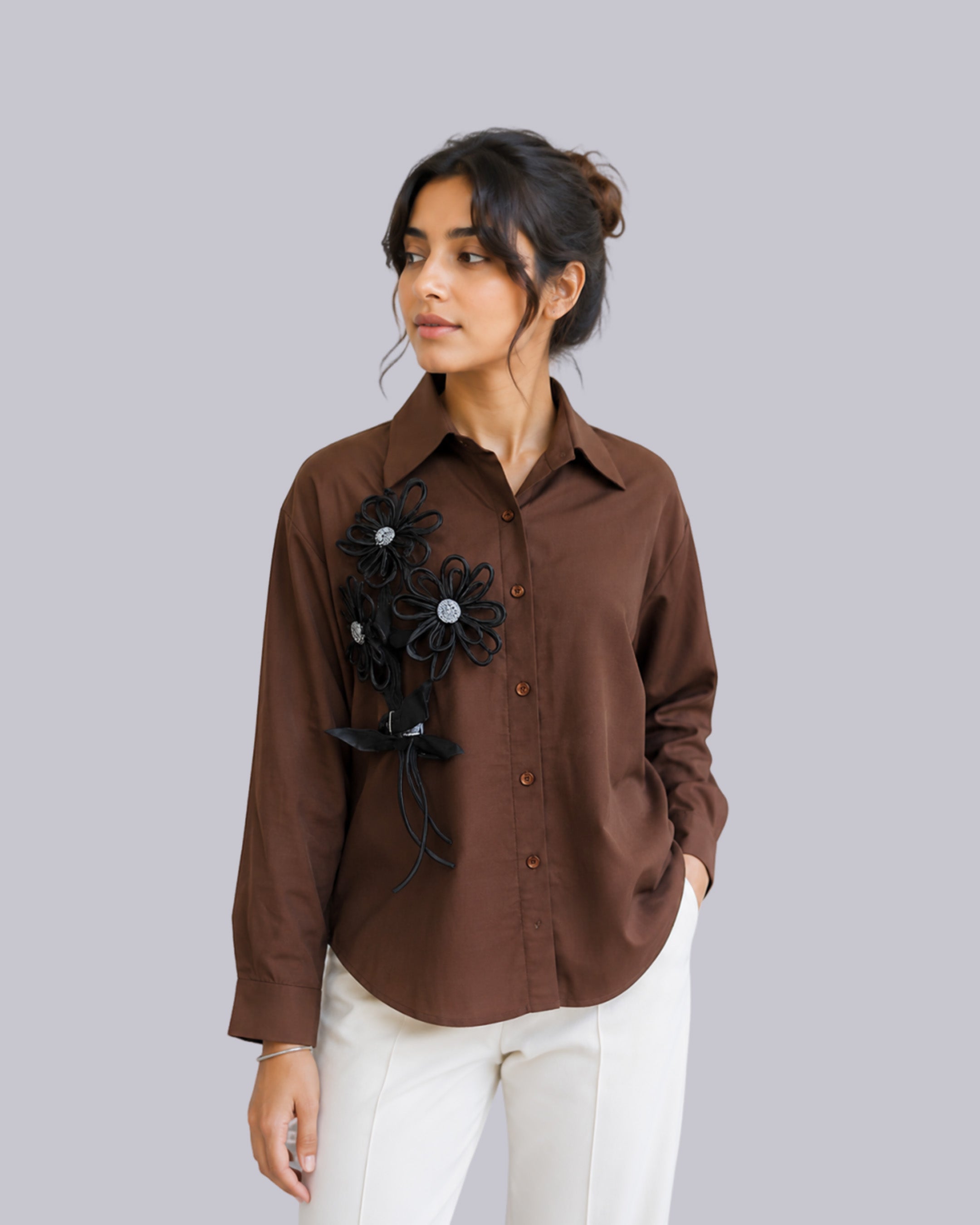 A woman wearing a brown button-up shirt .