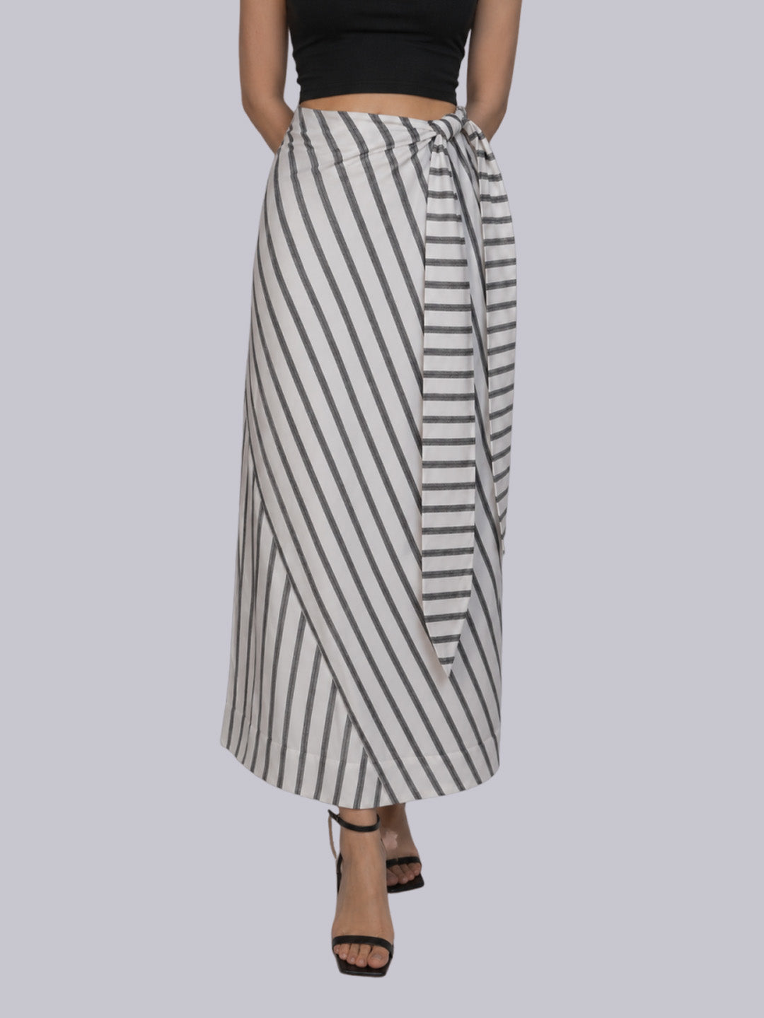 A model wearing a high-waisted, wrap-style maxi skirt with vertical black and white stripes.