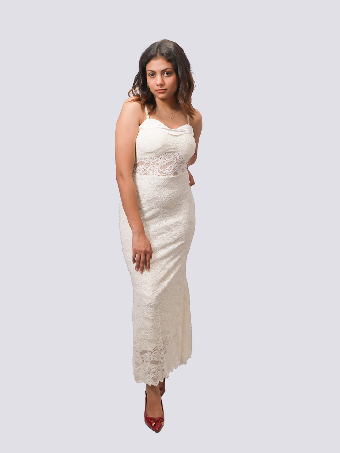 A woman modeling a sleeveless, off-white lace maxi dress with a cowl neckline and a fitted silhouette.