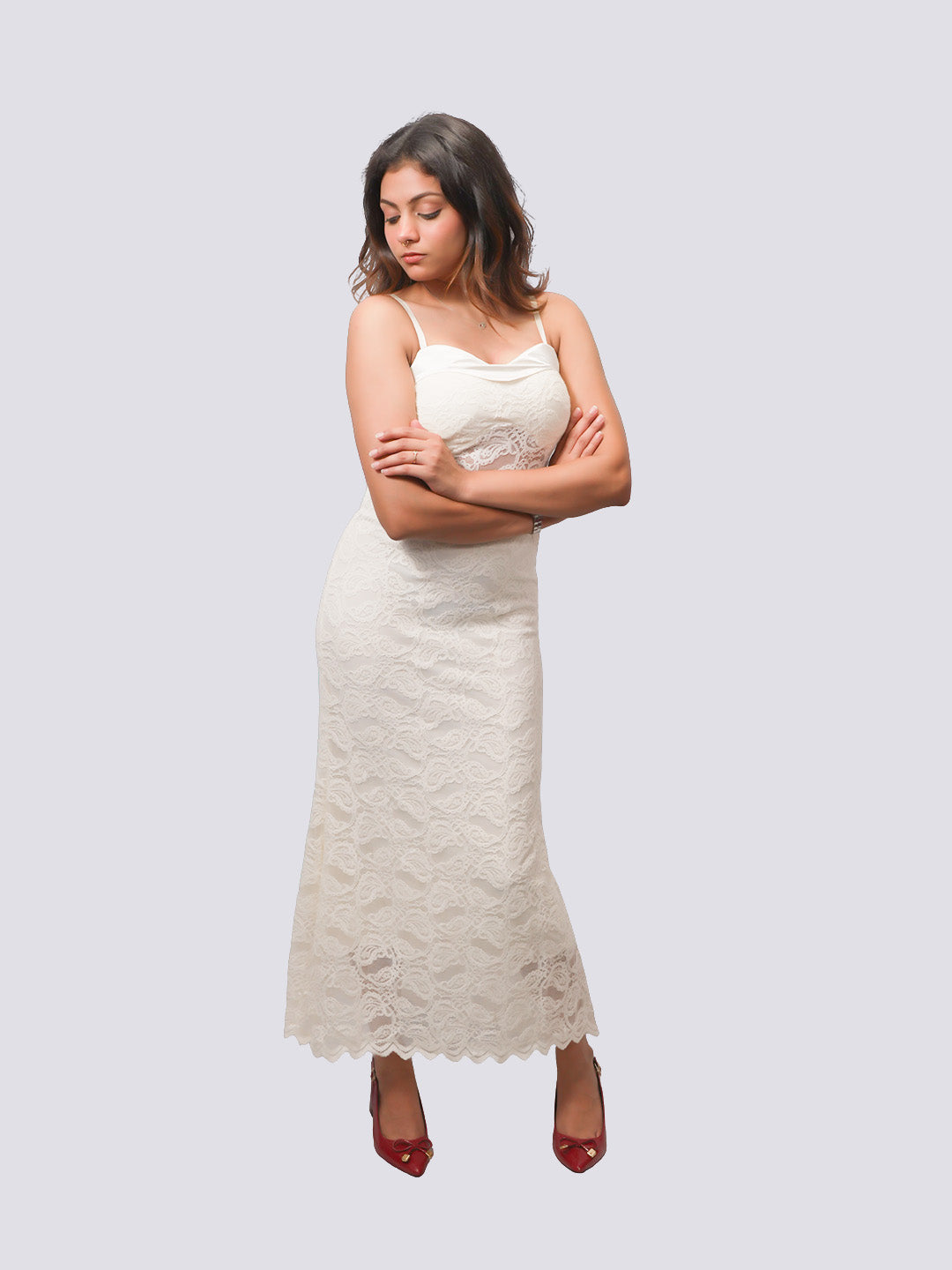 A woman modeling a cream lace spaghetti-strap maxi dress with a fitted bodice and flared lace skirt.