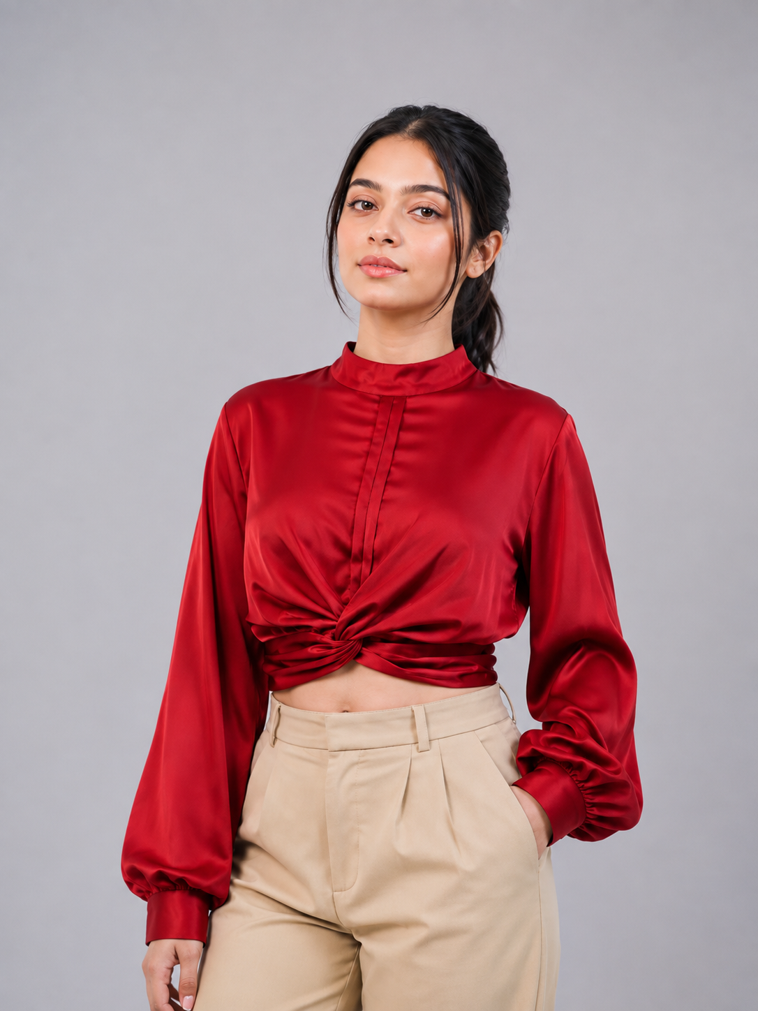 A long-sleeve red satin blouse with a gathered mock neck and front twist