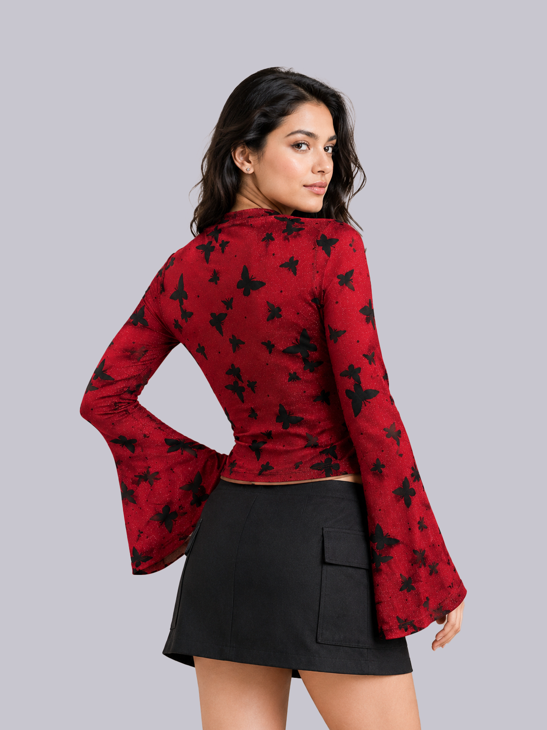 A woman modeling a red long-sleeve crop top with a black butterfly pattern, paired with a black mini skirt.
