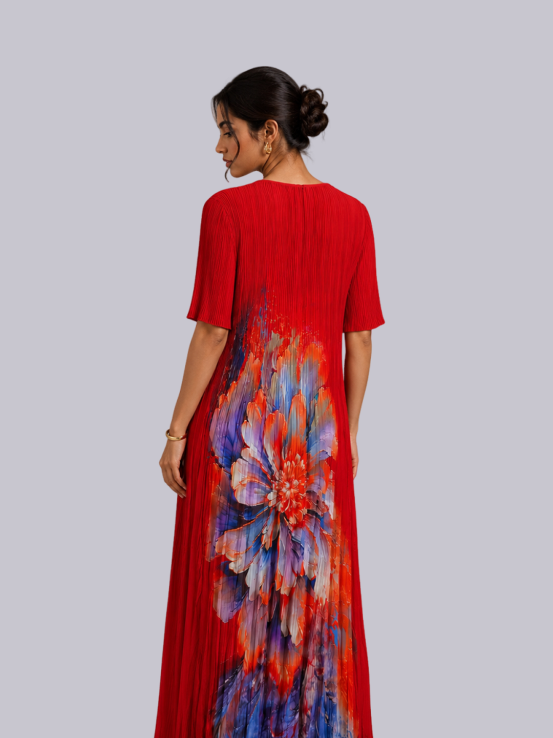 A woman shown from the back wearing a red short-sleeve maxi dress with a large colorful floral print in blue.