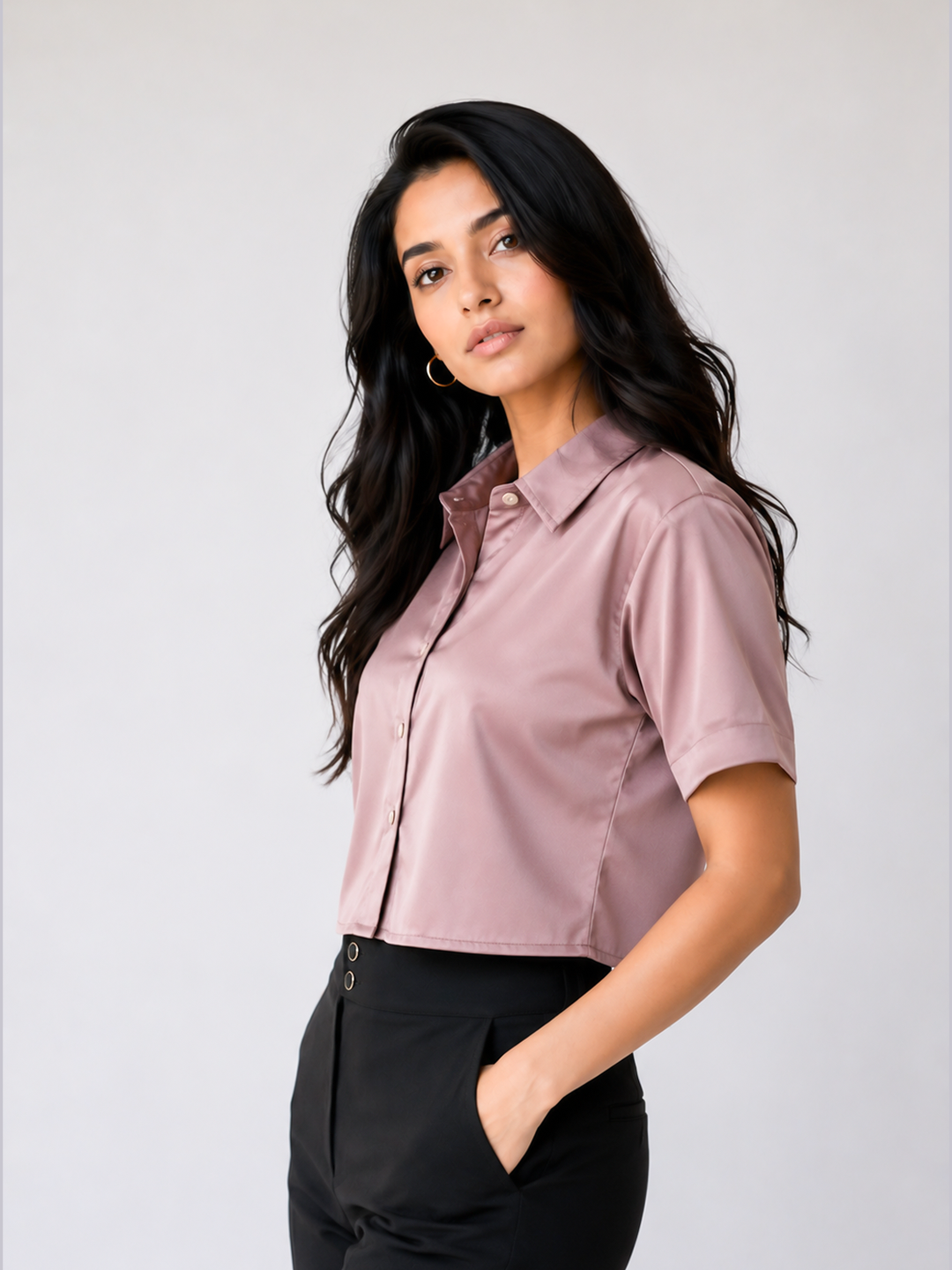 A woman with long, wavy black hair is wearing a short-sleeve, collared button-up blouse in a dusty mauve-pink color.
