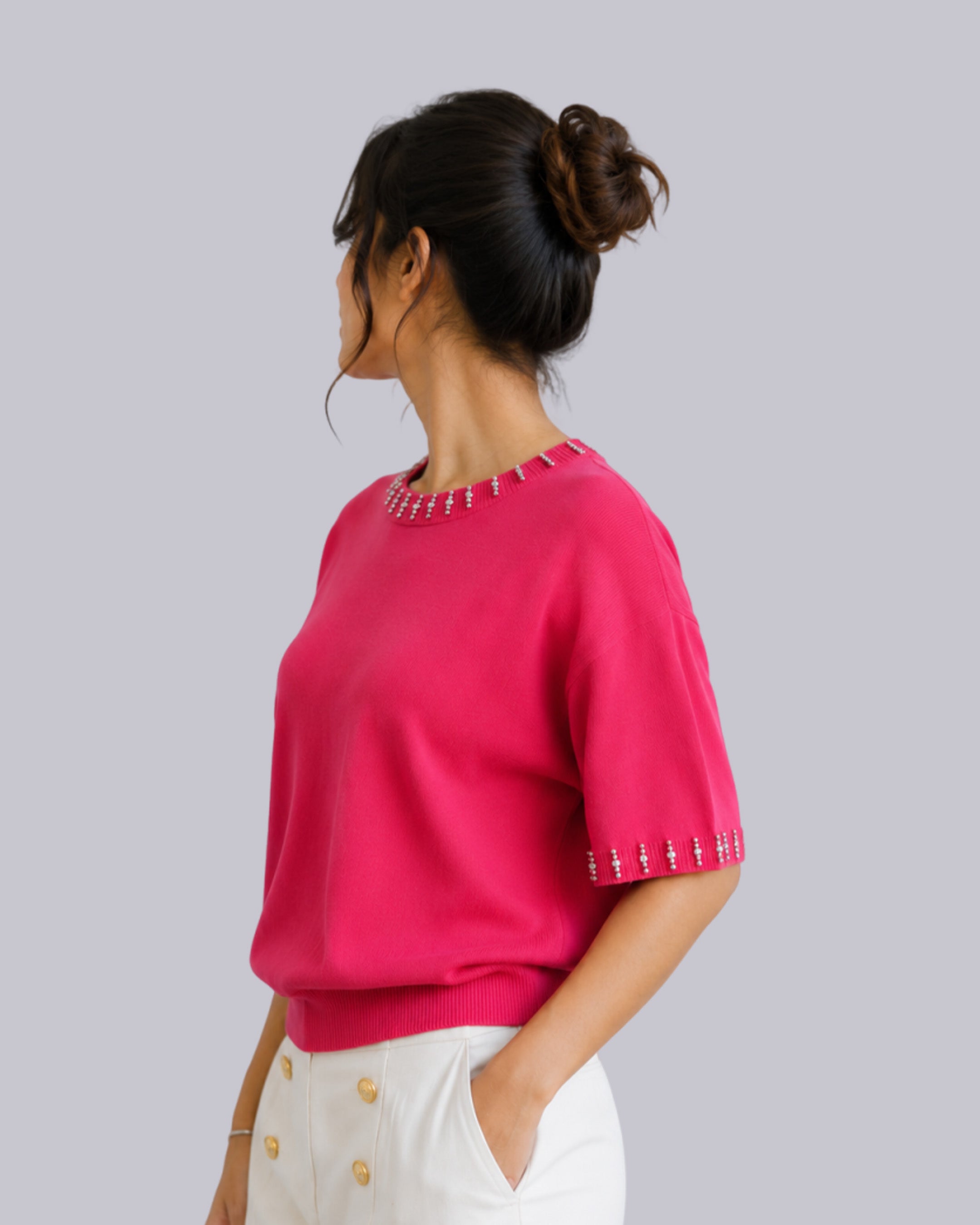 A woman shown from the side/back wearing a bright pink short-sleeve knit top 
