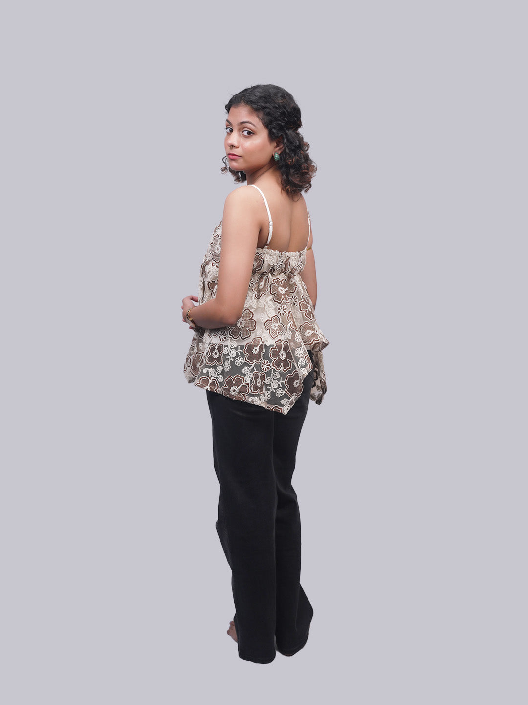 A woman is shown from the back wearing a sleeveless ruffled top.