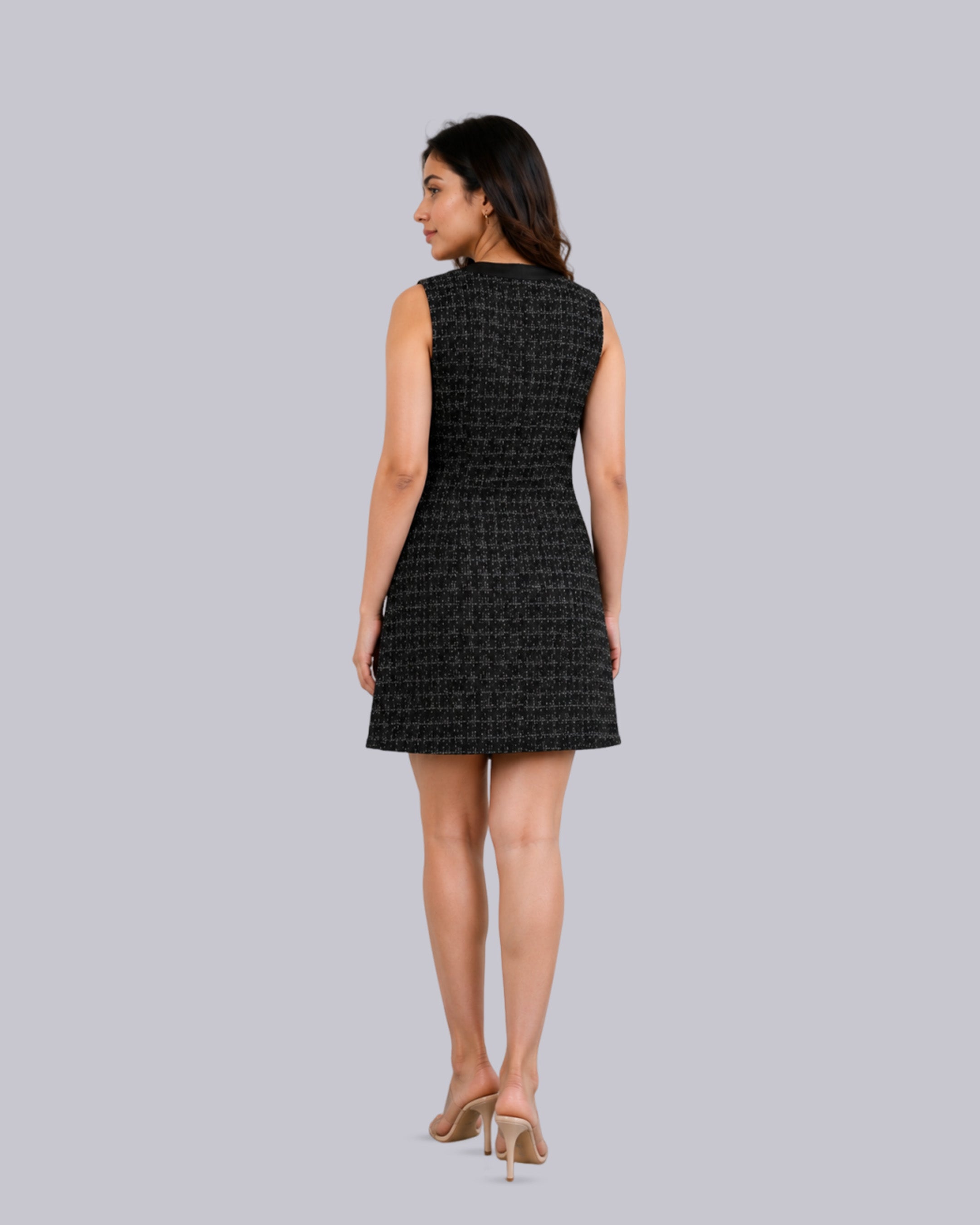 A woman shown from the back wearing a sleeveless black tweed mini dress.