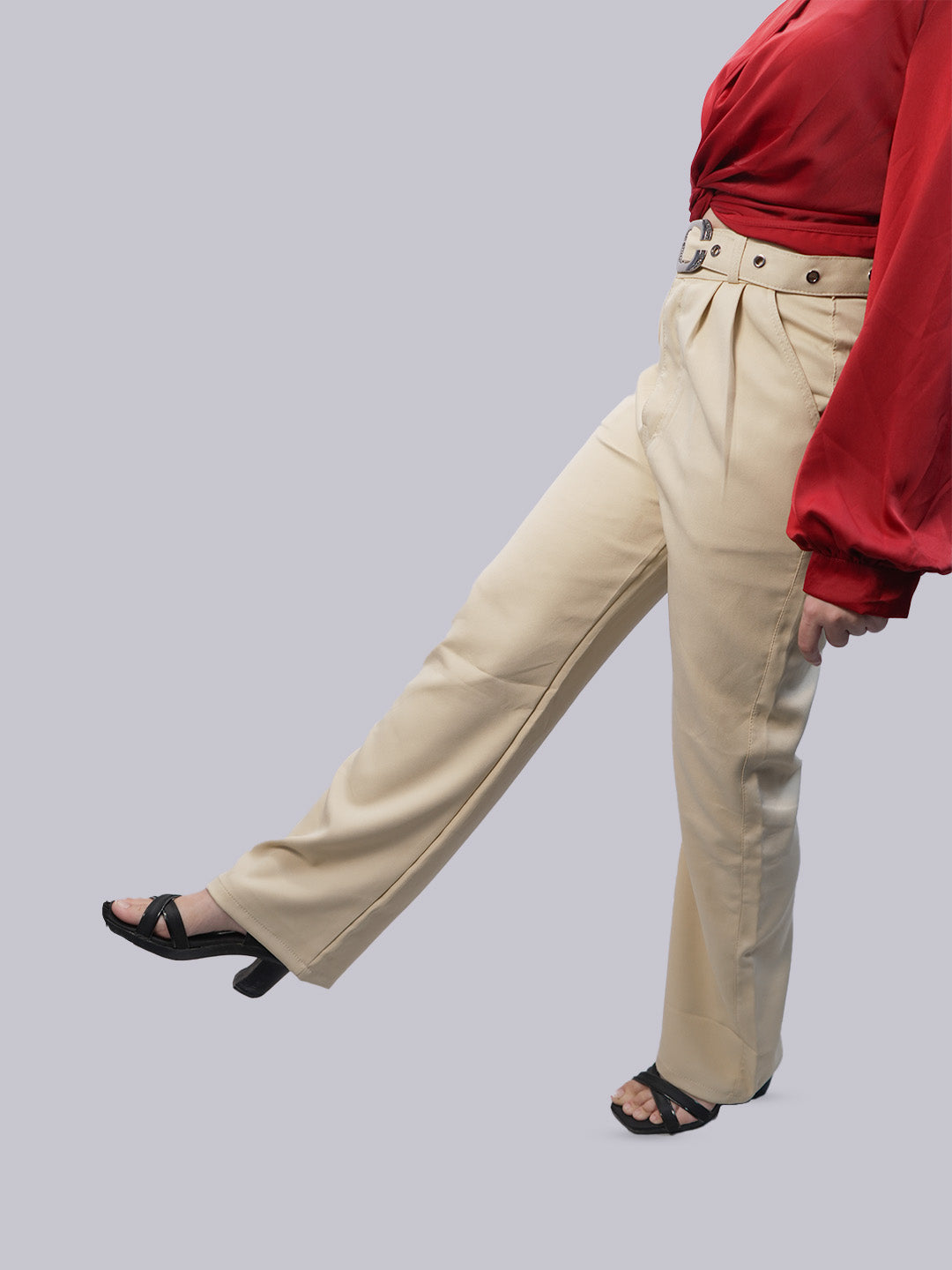 A person wearing high-waisted, wide-leg beige trousers with a matching belt.