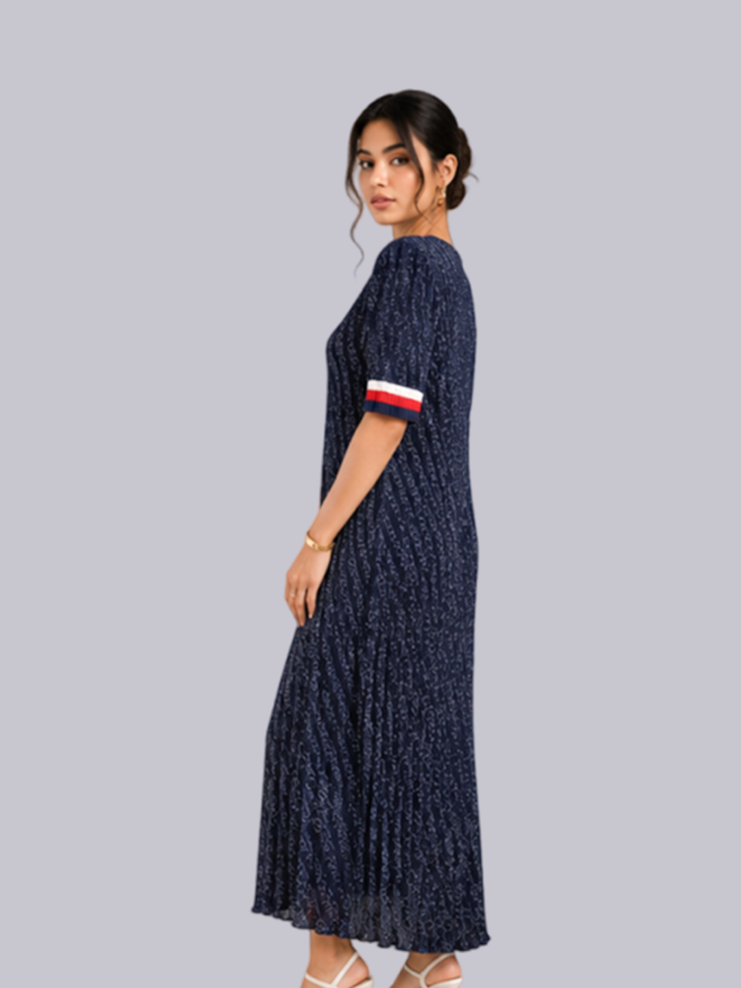 A woman modeling a navy blue maxi dress with a textured pattern and a red, white, and blue striped sleeve.