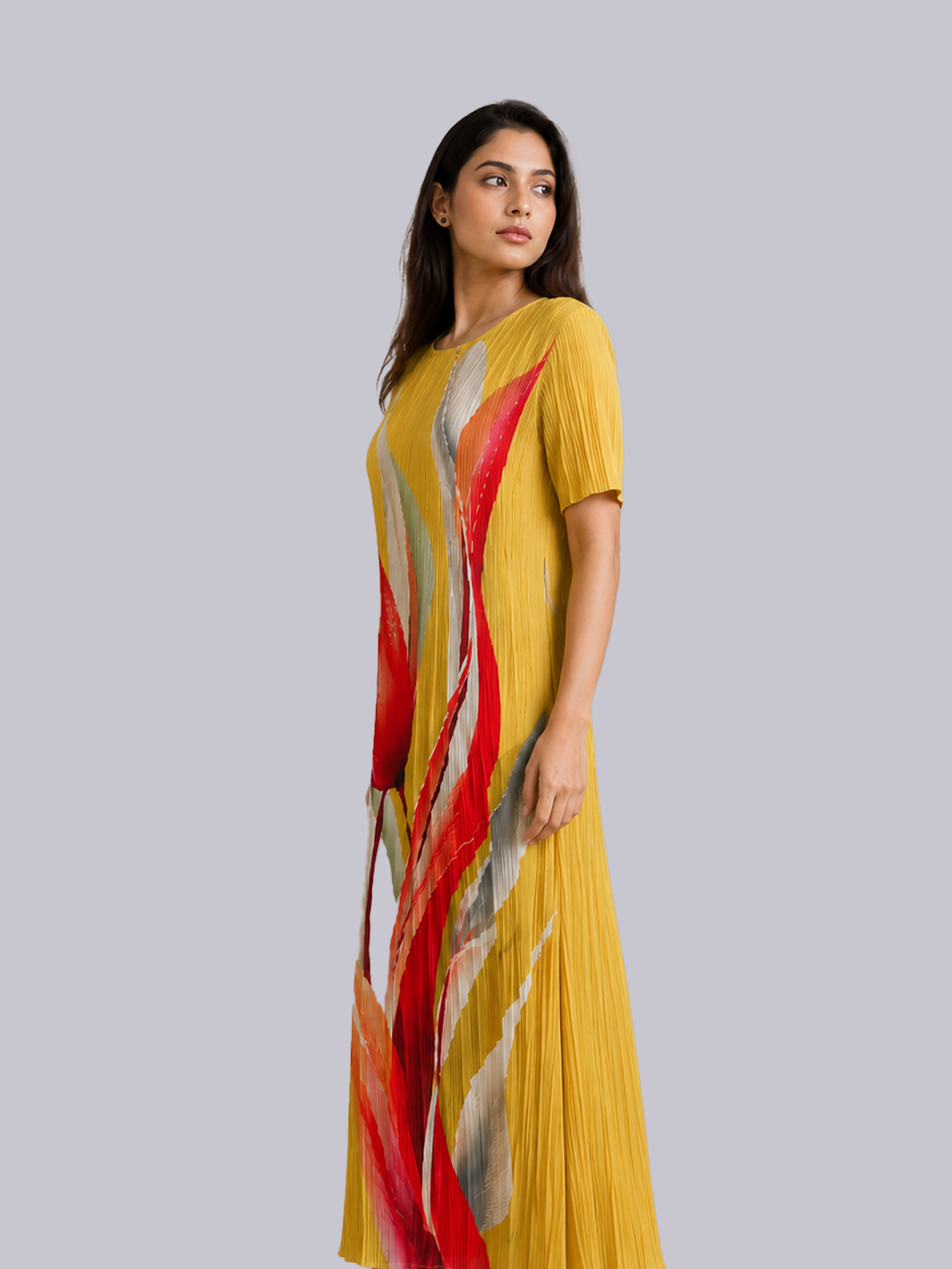 A woman modeling a yellow pleated maxi dress with abstract red, orange, and gray brushstroke patterns.
