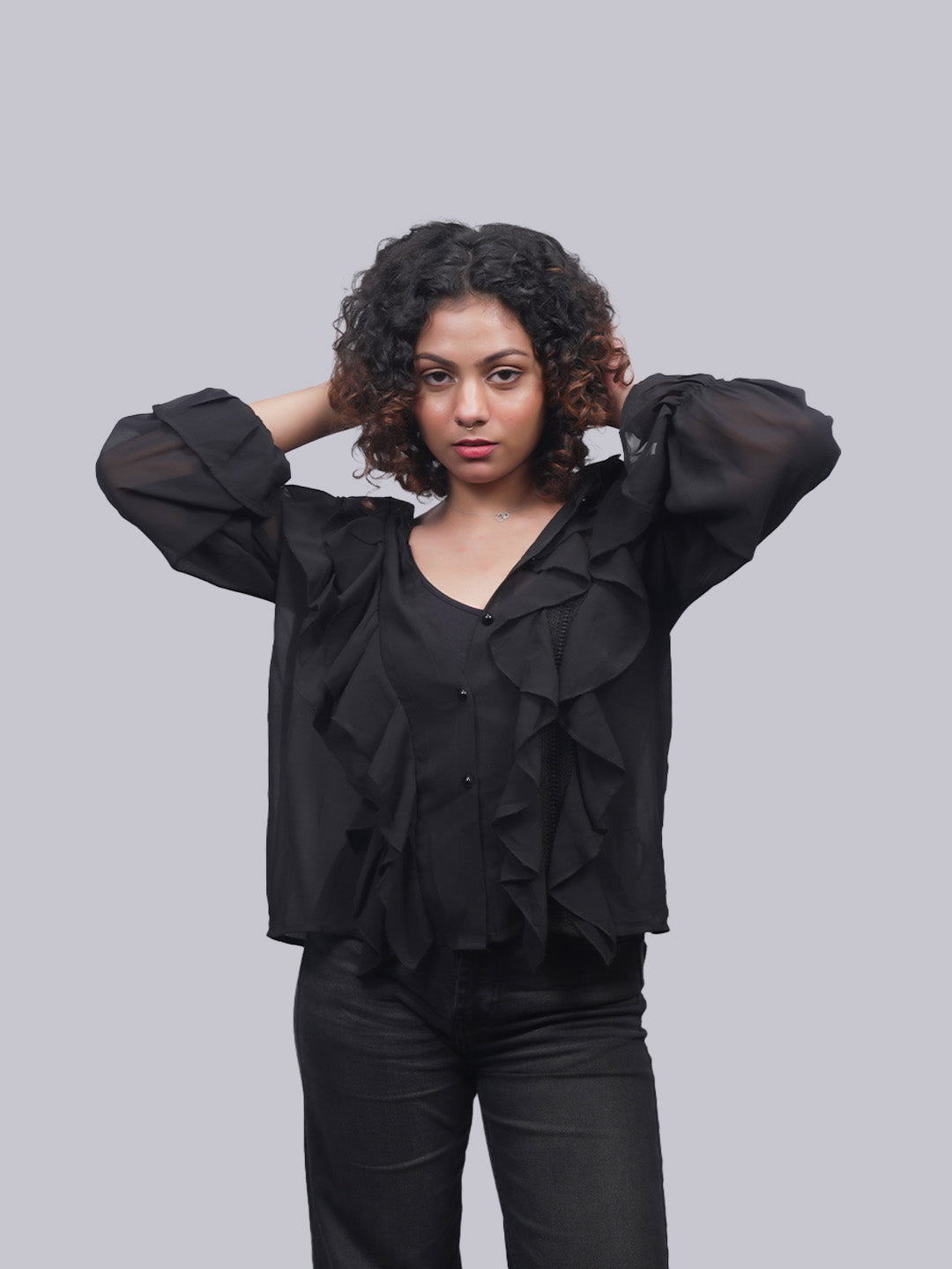 A woman with curly dark hair wearing a black ruffled top.