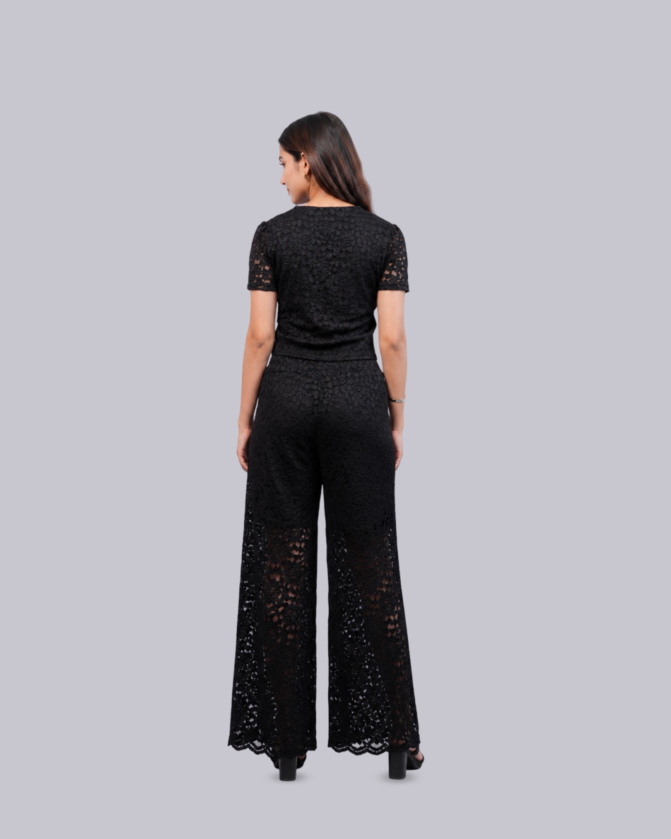 A woman viewed from the back wearing a black short-sleeve lace top.