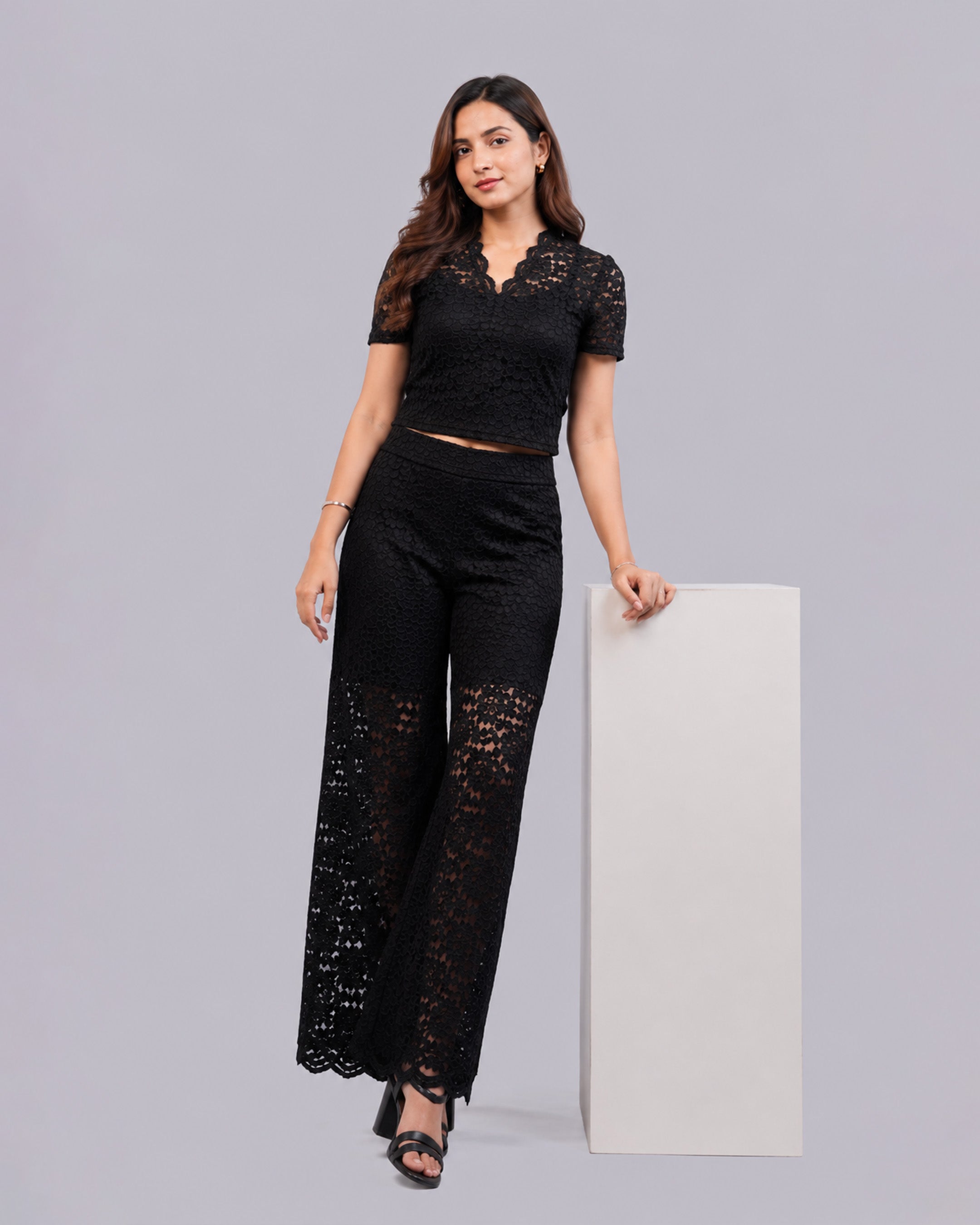 A woman modeling a black lace two-piece outfit.