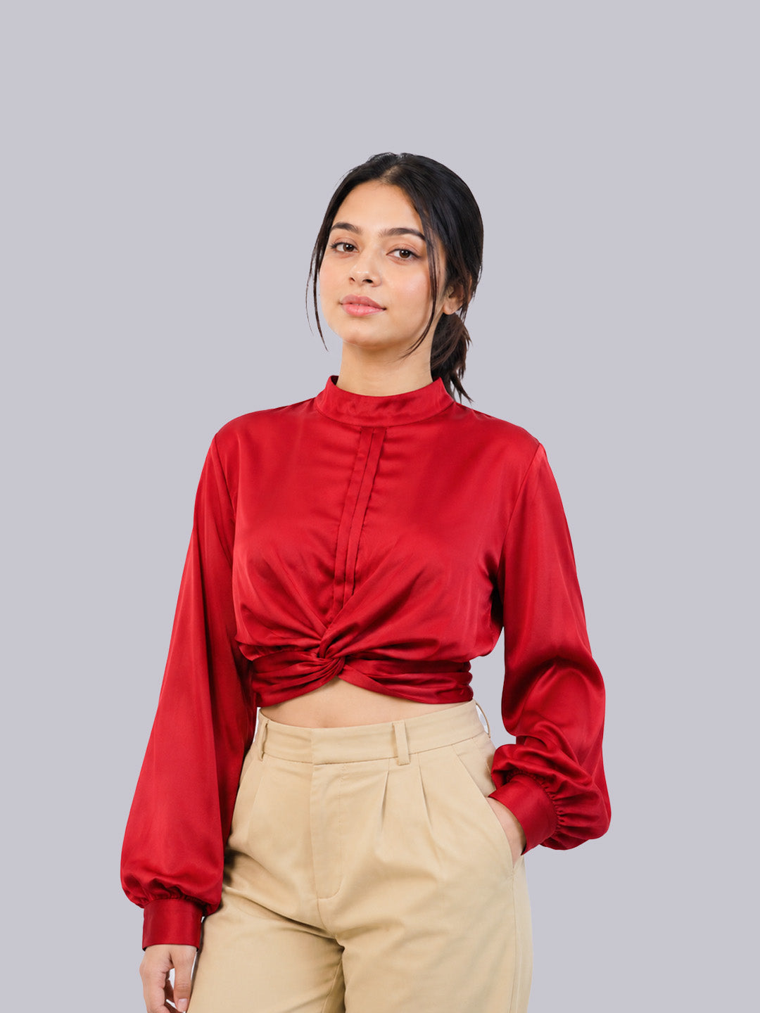 A woman modeling a red long-sleeve satin crop top.