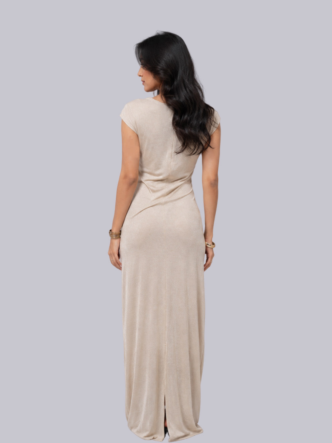 The back wearing a floor-length beige dress.